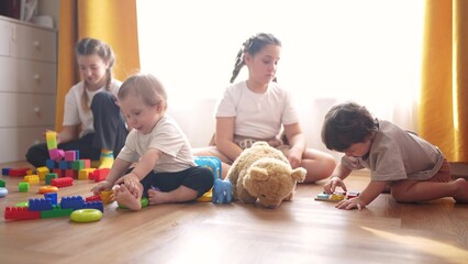 little children play at home. happy and full of joy childhood, children's dream concept. a group of children of different ages are playing in the room lifestyle, various colorful toys lie nearby