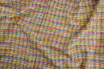 Texture of draped multi-colored tweed woven fabric textile background, Chanel style classic fabric, top view.