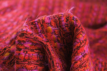 Close-up of texture of draped red tweed woven fabric textile background, Chanel style classic fabric.