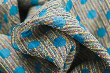Close-up of the texture of a draped multi-colored wool woven wool background with a polka dots blue, classic Chanel style fabric.