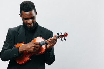Talented African American man in suit playing the violin on a white background in a professional studio setting - obrazy, fototapety, plakaty