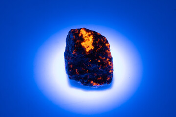 natural yooperlite gem stone in uv light on the white background