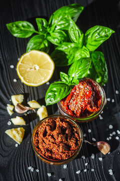 fresh pesto sauce with sun-dried tomatoes on a black wooden rustic background