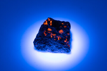 natural yooperlite gem stone in uv light on the white background