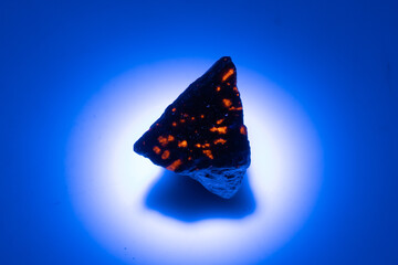 natural yooperlite gem stone in uv light on the white background