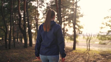 girl tourist walks through the forest. tourist trip concept. a young happy girl in a blue jacket...