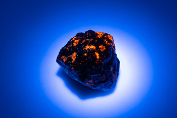 natural yooperlite gem stone in uv light on the white background