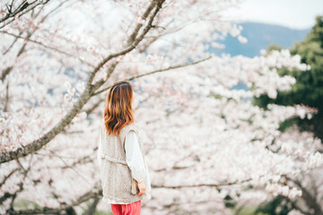 桜を見上げる茶髪の若い女性