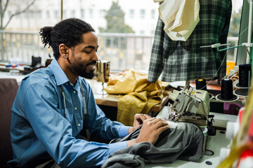 African American man fashion designer sewing on a vintage sewing machine.