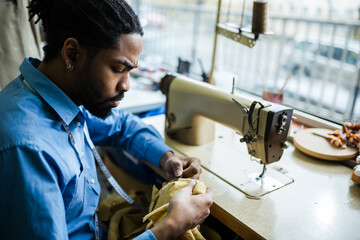 African American men fashion designer,tailor measuring fabric in his atelier.