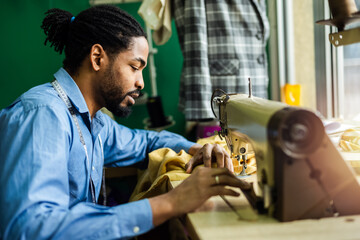African American man fashion designer sewing on a vintage sewing machine.