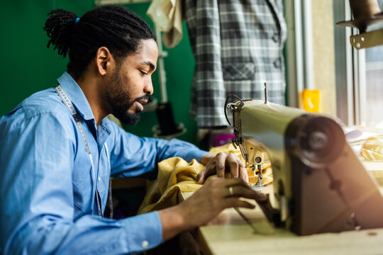 African American man fashion designer sewing on a vintage sewing machine.