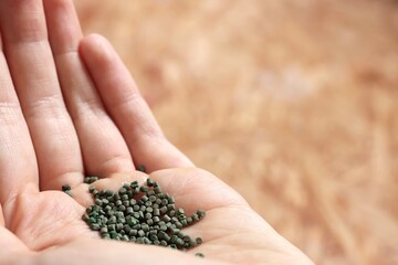 Hand of a Farmer throwing fertilizer on a field in a garden to grow plants efficiently symbolizing...