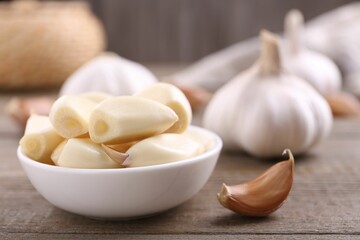 Aromatic garlic cloves and bulbs on wooden table, closeup. Space for text