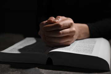 Religion. Christian woman praying over Bible at table, closeup