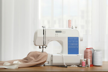 Sewing machine with fabric and craft accessories on wooden table indoors