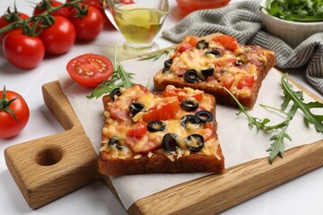Tasty pizza toasts and ingredients on white table