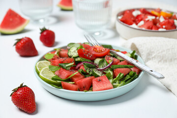 Watermelon salad in a bowl with strawberries and lime