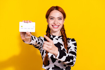 Photo of cheerful positive lady dressed cowskin print top pointing finger bank card isolated yellow...