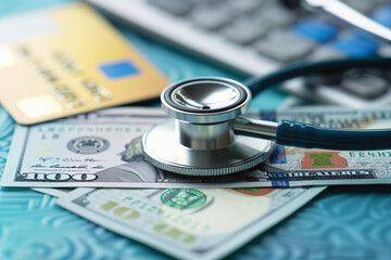 Stethoscope on money and credit cards, symbolizing medical costs.