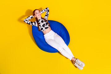 High angle view of lovely person sit comfy bag arms behind head chill isolated on yellow color...