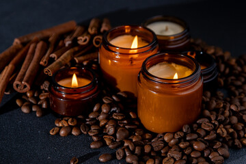 Soy scented candle in a jar. Coffee beans, anise, cinnamon spices. The candles are burning. Dark...