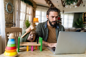 Multi-tasking freelance and fatherhood concept. Working single father with child and laptop computer