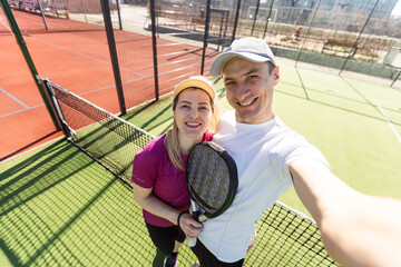 Paddle tennis woman and man team posing in wide angle image
