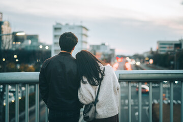 歩道橋から夜景を眺めるカップルの後ろ姿