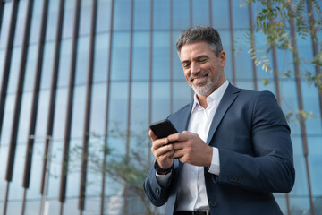 Portrait of smiling executive ceo manager. Latin adult man in suit using smartphone application app...