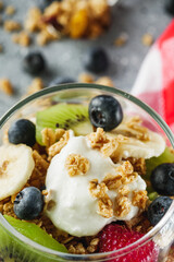 delicious crunchy granola dessert with berries and fruits on a gray stone background