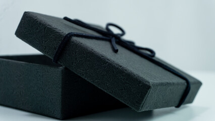 Black gift box with texture with black ribbon isolated on white background. The gift box is open