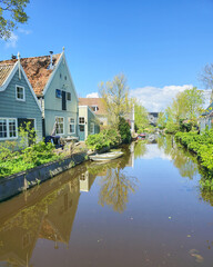 A peaceful river flows through a charming small town in the Netherlands, surrounded by traditional houses on either side