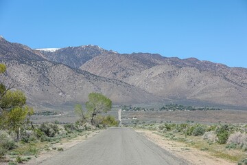 empty road through a desert valley surrounded by mountains and barren vegetation