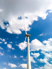 A tall wind turbine gracefully spins in the center of a clear, blue sky, harnessing the power of...