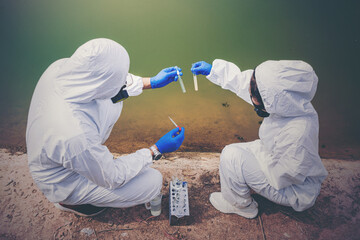 Scientists with protective suit holding a test tube with sample water in their hands. Water...