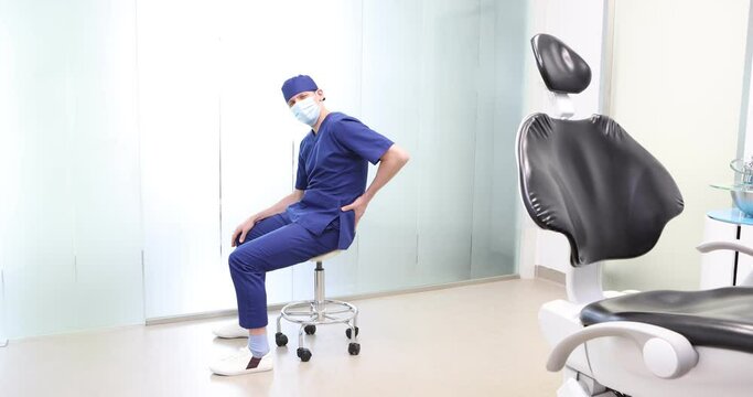 Sitting dentist, dealing with lower back pain.Symptoms and self help exercises, stretching. Profile view.