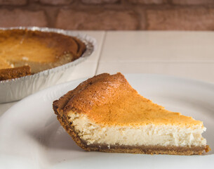 Cheese Cake or Cheese Pie slice on a white plate and a cheese pie container in the background