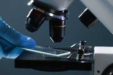 Scientist working with microscope on dark background, closeup
