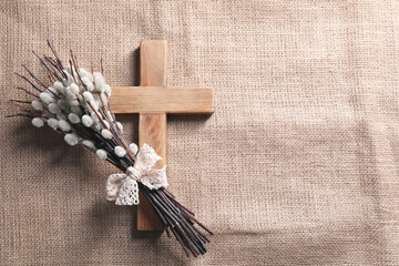 Cross and willow branches on beige cloth, flat lay. Space for text