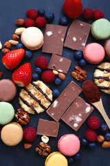 Macarons, chocolate, cookies, berries and various nuts on dark blue background. Top view.
