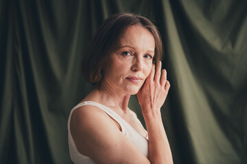 Unretouched portrait of old lady touch face feel tenderness isolated green color linen background