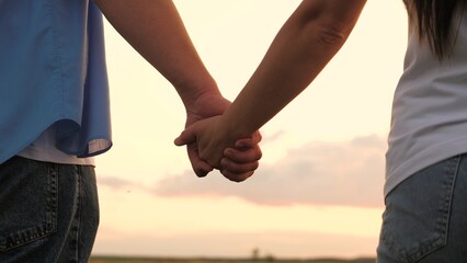 Couple man and woman taking hands to each other at sunset sky summer meadow romantic date closeup....