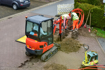 Die Arbeiter verlegen das Glasfaserkabel f&uuml;r das schnelle Internet auch bei schlechtem Wetter routinem&auml;ssig