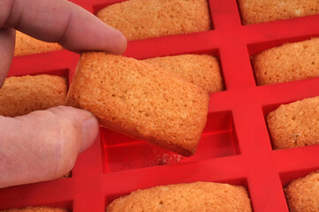 Prendre un financier aux amandes avec les doigts dans un moule en silicone en gros plan