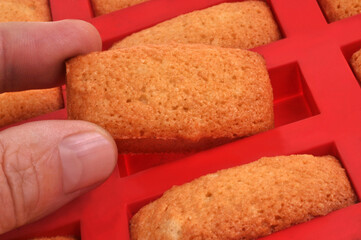Prendre un financier aux amandes avec les doigts dans un moule en silicone en gros plan