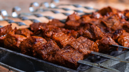 Marinated skewers are prepared on a barbecue grill over charcoal. Shish kebab or shish kebab is...