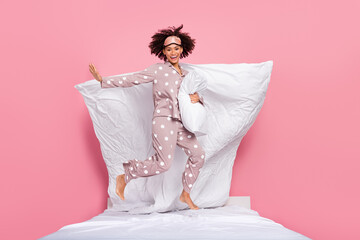 Photo of positive sweet lady wear pajama jumping high cuddling pillow isolated pink color background