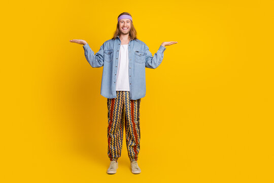 Full body photo of attractive young hippie man compare empty space wear trendy denim outfit isolated on yellow color background