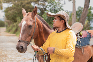 ifestyle: latino farmer in yellow shirt next to his horse